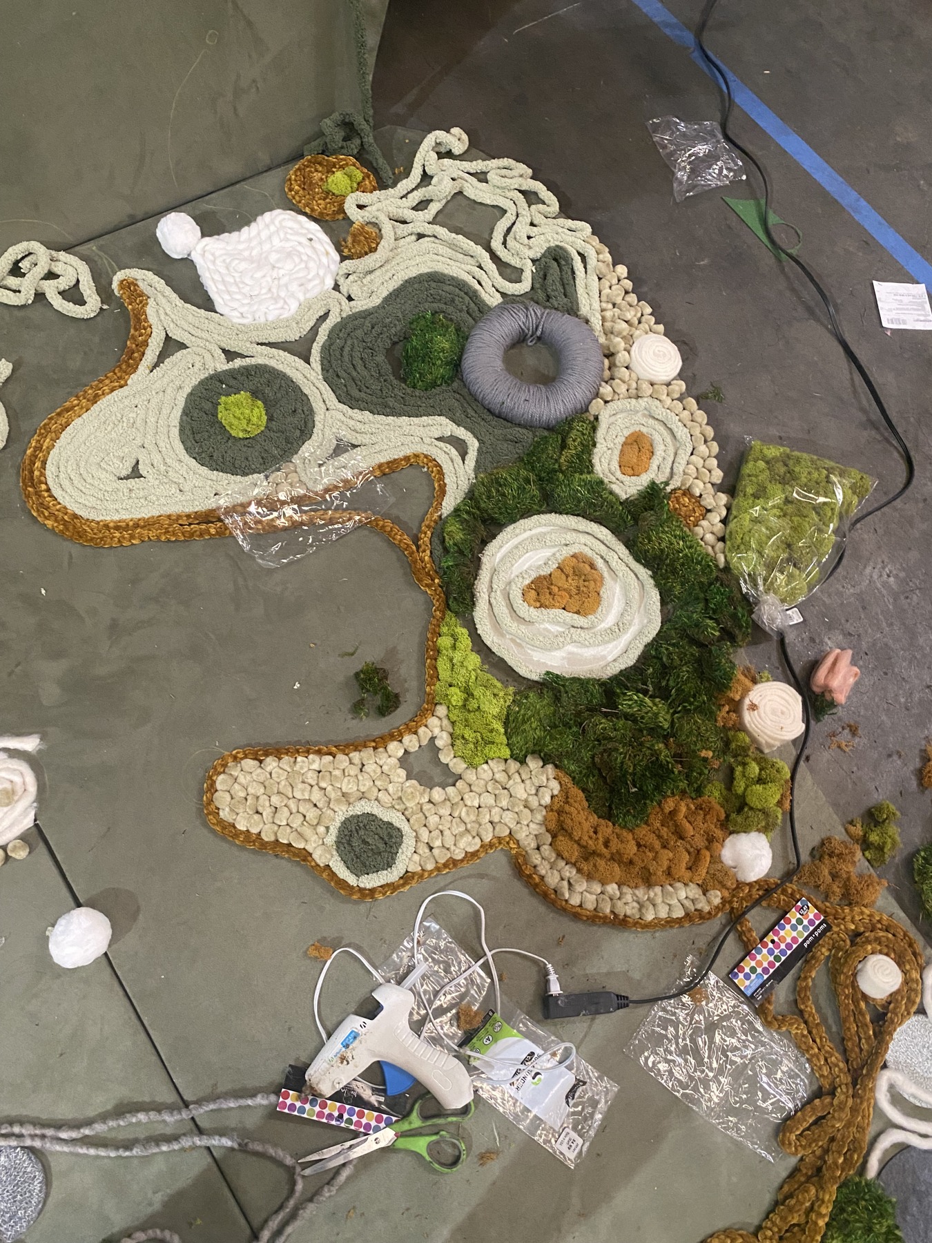 Building the composition with moss, rope, and sculptural details.